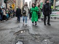 Valérie Plante in a green coat approaches a pothole during a parade