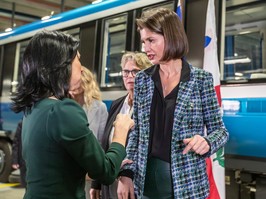 Montreal Mayor Valerie Plante and Transport Minister Genevieve Guilbault, two white woman, are facing each other and seemingly having a conversation in front of a metro car.