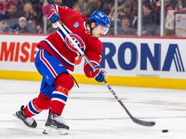 Canadiens' Arber Xhekaj, wearing the Habs' home red jersey, is seen stepping into a slapshot, with the puck just leaving his stick.