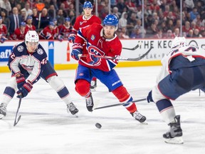 Canadiens' Alex Newhook skates between Blue Jackets' Alexandre Texier, left, and Erik Gudbranson during a game last month at the Bell Centre.