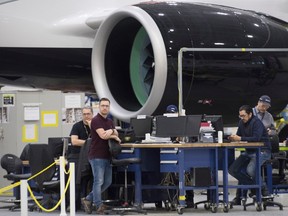 Airbus employees work next to the engine of Airbus A220 at the assembly plant in Mirabel,