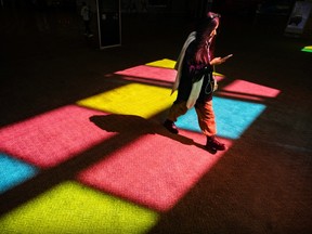 A woman crosses a carpet that is reflecting red, yellow and blue windows.