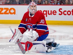 Canadiens goalie is seen in the butterfly position in front of his net, sporting the Habs' red home jersey, as he looks up into the crowd following a puck that went out of play with his eyes.