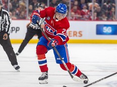 Canadiens' Kaiden Guhle, wearing the team's home red jersey, is seen firing the puck into the offensive zone during a game in March.