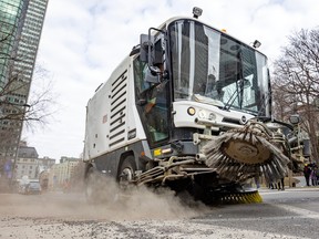 A street sweeper kicks up dust in a photo from a low angle