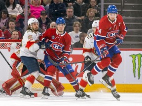 Canadiens' Nick Suzuki jumps away from a teammate's shot as Juraj Slafkovsky sets up in front of the Panthers net defended by Ryan Lomberg, left, and Brandon Montour during second period Tuesday night at the Bell Centre.