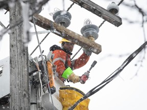 A worker is seen working on power lines in the snow