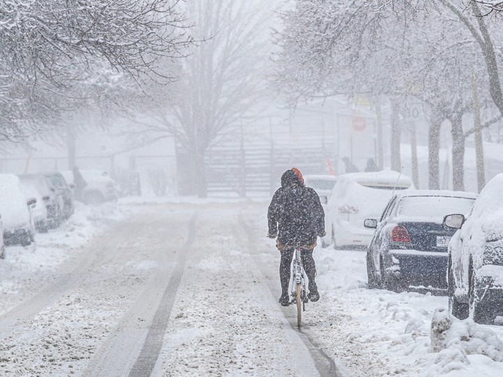 A cyclist makes her way through the snow on Workman St. in Montreal on Thursday April 4, 2024.