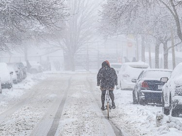 A cyclist rides down a snowy street