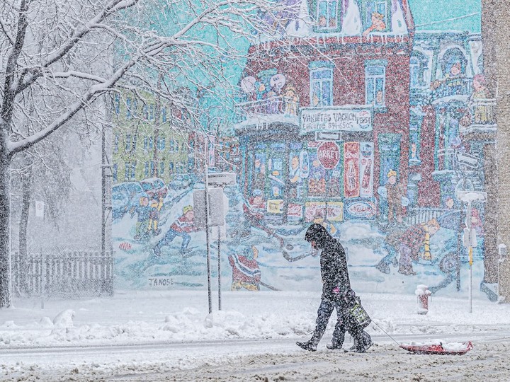 A man and child cross Wellington St. in Verdun during a snowstorm April 4, 2024.
