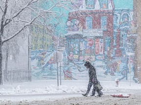 A man and child walk hand in hand with a sled behind them. They are passing a mural of a Montreal street.