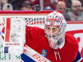 A close-up of Canadiens goalie Cayden Primeau, wearing the traditional Habs home red jersey, as he makes a blacker save while keeping his eyes on the puck.