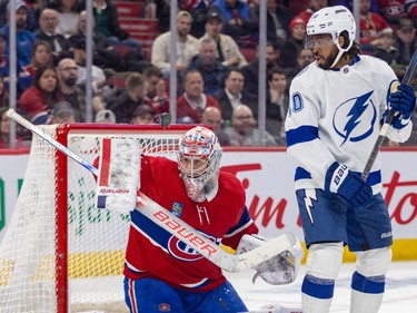 Tampa Bay Lightning's Anthony Duclair looks over his shoulder at a puck midair in front of the crossbar above a kneeling Canadiens goalie