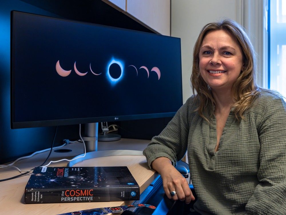 A woman sits by a computer screen displaying phases of an eclipse.
