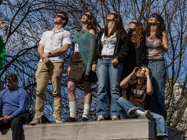 People wear eclipse glasses while standing on a stairway.