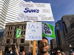 A striking teaching assistant at McGill University holds an eclipse-themed sign that says: Even the sun is on strike.