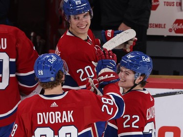 Canadiens players smile as they interact on the ice