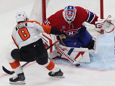 The puck sits on the ice in front of the Canadiens goaltender's stick as Flyers' York skates by