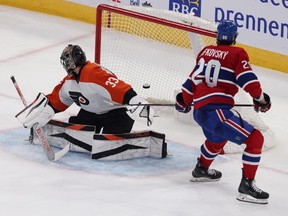 The puck is midair in the Flyers net as the goalie looks behind him and Canadiens' Slafkovsky skates by