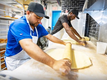 Two men roll dough in a restaurant kitchen