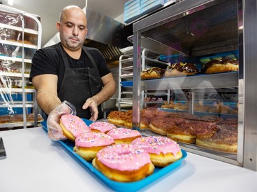 Owner Terry Axiotis makes a display tray of doughnuts in the fryer at Homer's Donuts in Montreal's N.D.G. district Wednesday April 10, 2024.