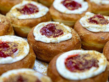 A closeup photo of doughnuts with a ring of white icing and a red jam in the middle