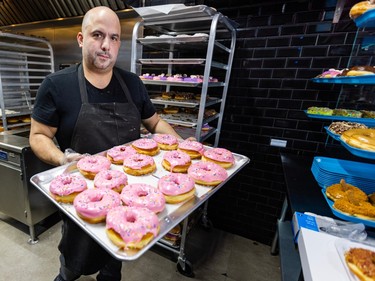 Terry Axiotis carries a tray of doughnuts at his Homer's shop in N.D.G. April 10. He said he's been overwhelmed by the surprise popularity of the treat.