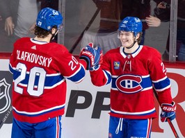 Cole Caufield smiles as he shakes hands with Juraj Slafkovsky on the ice