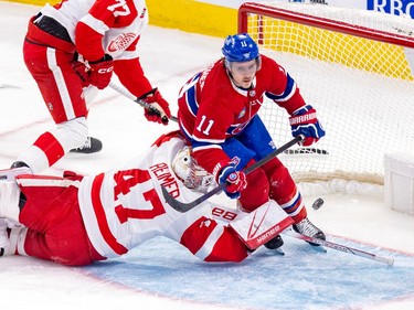 Canadiens' Brendan Gallagher skates through the goal crease with a puck in the net and Red Wings goalie James Reimer lying on the ice facing the goal