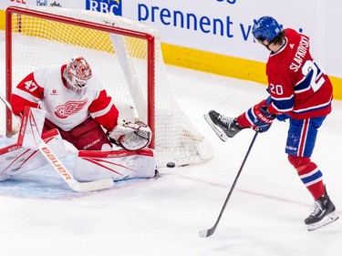 The puck sits outside the back of the net while Canadiens' Juraj Slafkovsky sticks his foot out ahead of him and Red Wings goalie James Reimer blocks the corner of the net