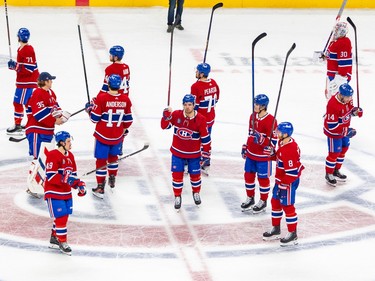 Canadiens players put their sticks in the air around centre ice