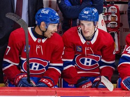 Canadiens defencemen Jayden Struble, left and Lane Hutson are seen on the Habs bench wearing the team's traditional home red jersey talking to one another during the team's season finale on Tuesday.