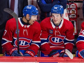 Canadiens defencemen Jayden Struble, left and Lane Hutson are seen on the Habs bench wearing the team's traditional home red jersey talking to one another during the team's season finale on Tuesday.