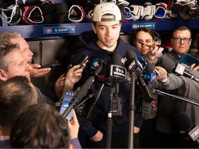 Canadiens' Nick Suzuki is surrounded by a throng of media members as he speaks from the Habs' dressing room at CN Sports Complex in Brossard