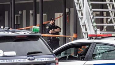A police officer stands outside a motel room entrance surrounded by orange crime scene tape