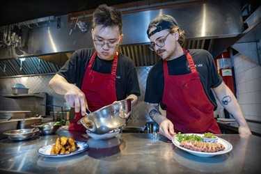 Chef Anderson Lee, left, and line cook Simon Desbiens prepare the duck platter for 2 in the kitchen at Oncle Lee restaurant in Mile End on Thursday, April 18, 2024.