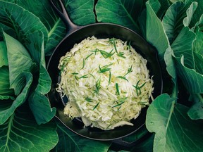 Wilted white cabbage in a cast-iron pan on a bed of cabbage leaves.