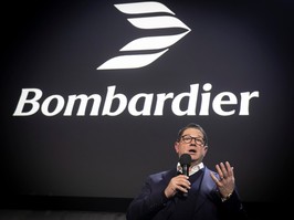 Bombardier president and CEO Eric Martel is seen in front of the company's new logo, which represents four wings of an airplane overlayed to form a sort of sideways V, making it look like two airplane wings. The shape of a jet's nose and fuselage is visible in the white space in the middle of the graphic.