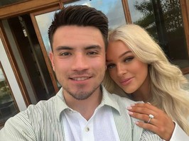 Nick Suzuki smiles in a selfie while Caitlin Fitzgerald stands behind him with her hand on his shoulder sporting an engagement ring