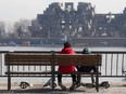 Two kids sit on a waterfront bench with their skateboards