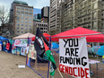 A sign that reads "You are funding genocide" can be seen amid an encampment on McGill's downtown campus
