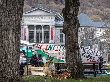 McGill's downtown campus is visible in the background behind people gathered at a makeshift encampment