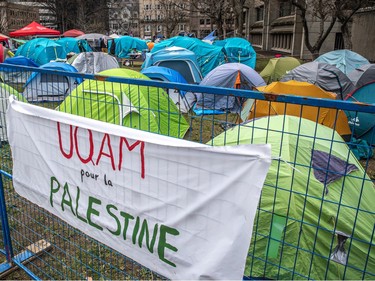 A banner reading 'UQAM pour la Palestine' is affixed to a fence with camping tents behind it