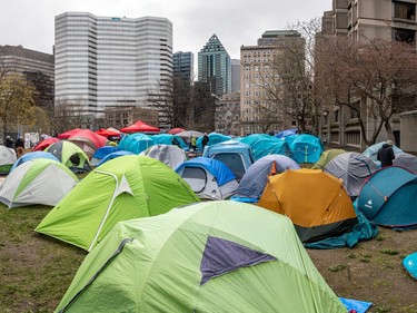 Dozens of tents are visible on a grassy area downtown