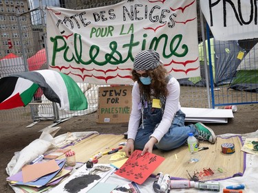 A woman makes signs using arts and crafts supplies at an encampment