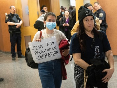 People walk out of a courtroom, one holding a handmade sign reading 'Jews for Palestinian liberation'