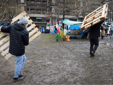 People carry wood shipping pallets through a muddy area
