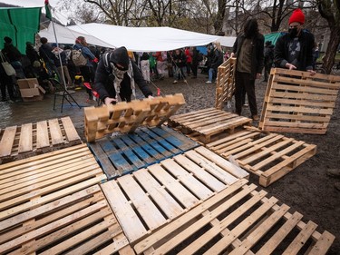 A series of wood shipping pallets are arranged on the muddy ground in an encampment