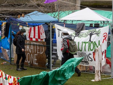 Two people are seen outside a temporary fence with banners tied to it
