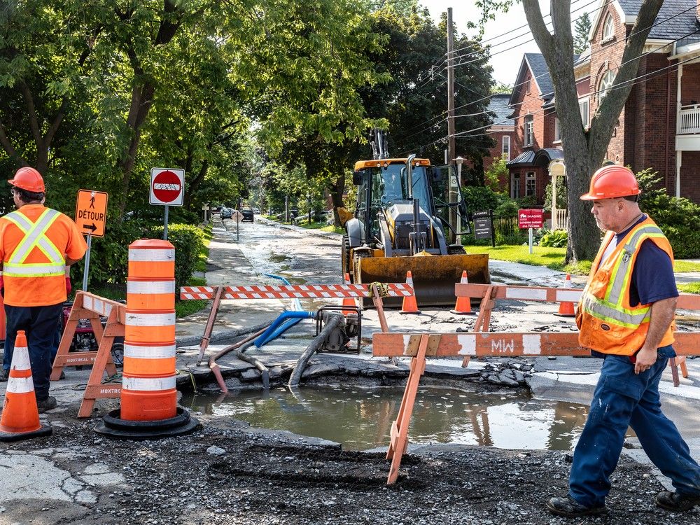 pothole filled with water and construction workers
